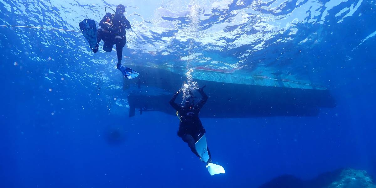 心海潛水教練正專注地指導一位進階潛水員進行水下安全演練，展現專業與安心的潛水學習氛圍，背景是清澈的墾丁海水與珊瑚礁。